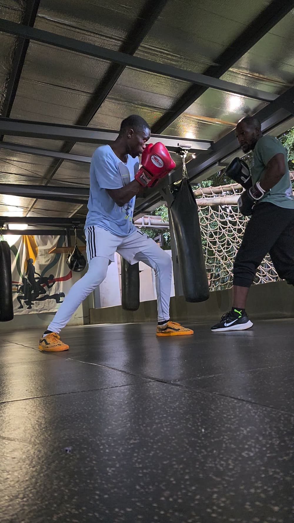 Tim holding pads for a client under the gym roof at night
